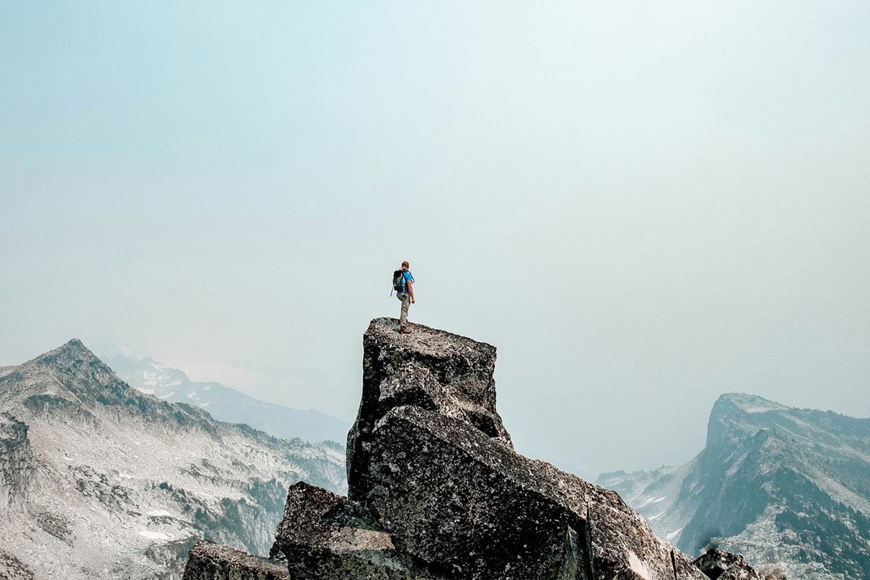 A man standing on top of a mountain looking into the distance.