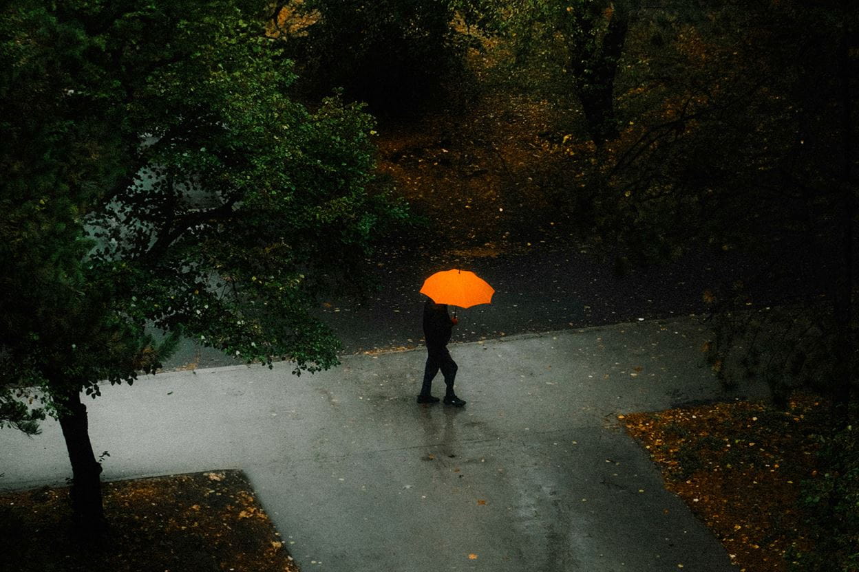 A man walking in the rain with an umbrella.