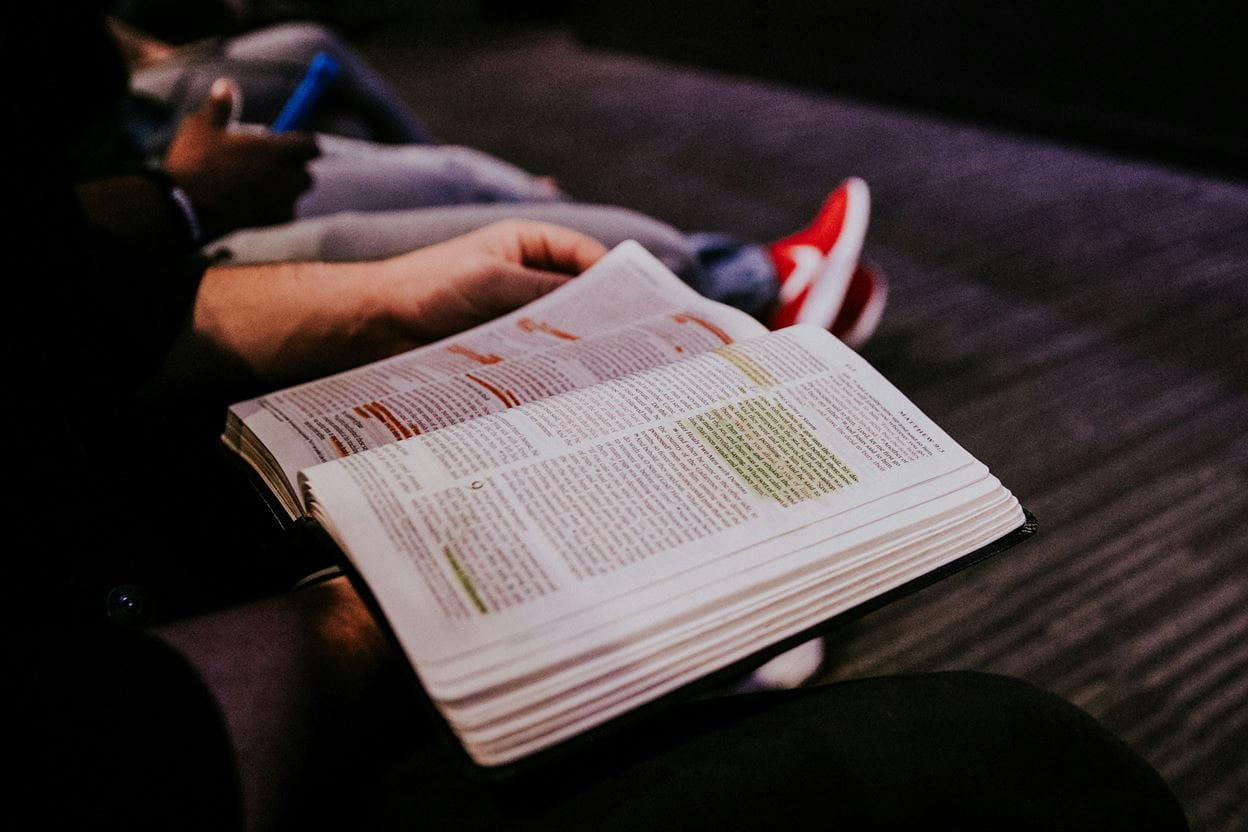 Image of a person sitting on a couch reading a bible