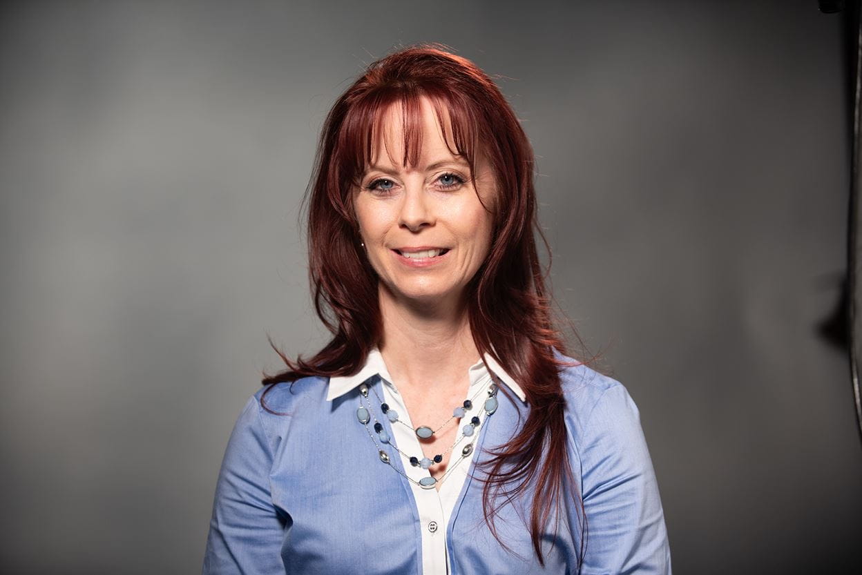 Woman Smiling in Front of Gray Background