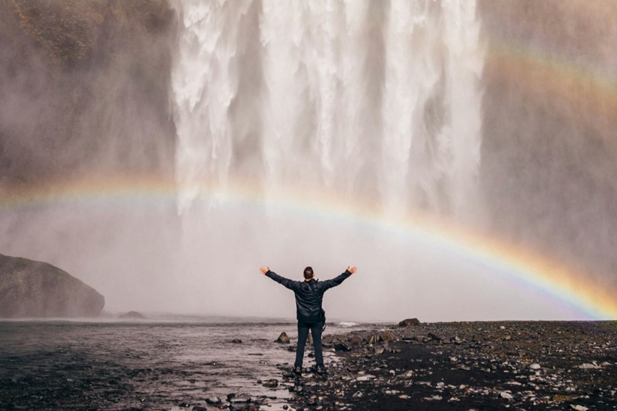 Image of a man standing in front of rainbow.