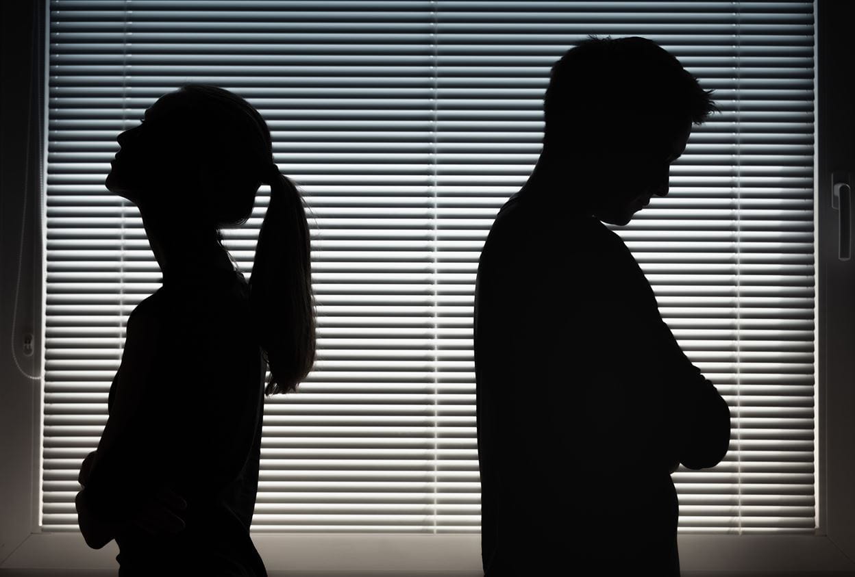 Silhouettes of a woman and man looking disappointed, with their backs turned to each other.