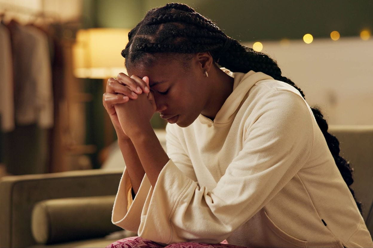A woman, kneeling with hands folded and praying.
