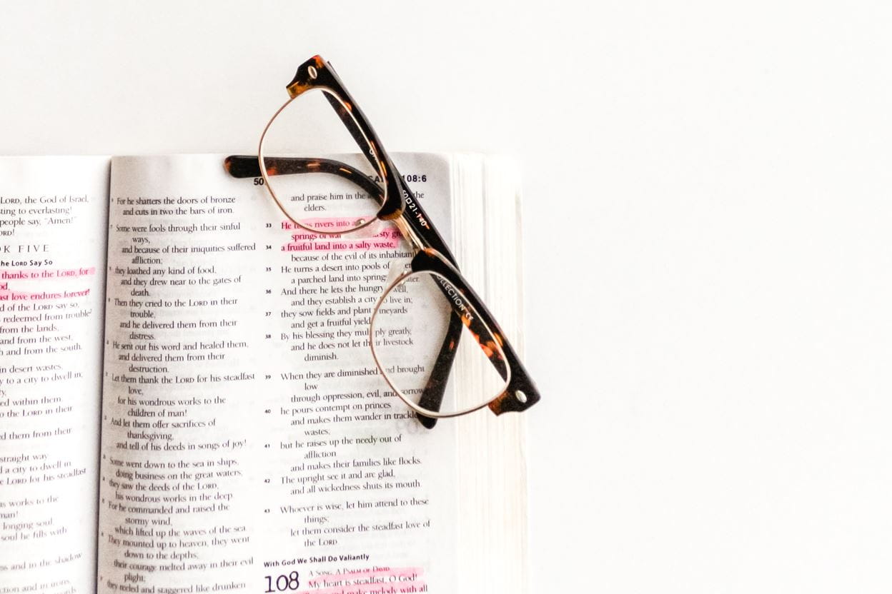 Eyeglasses sitting on an open Bible ready for reading a daily devotional.