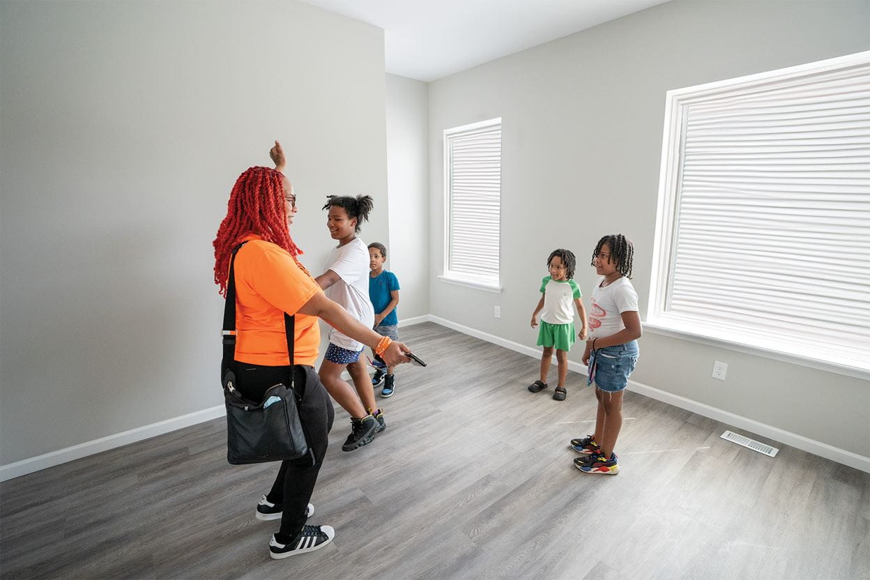 A mom and her children standing in a room of a brand new home.