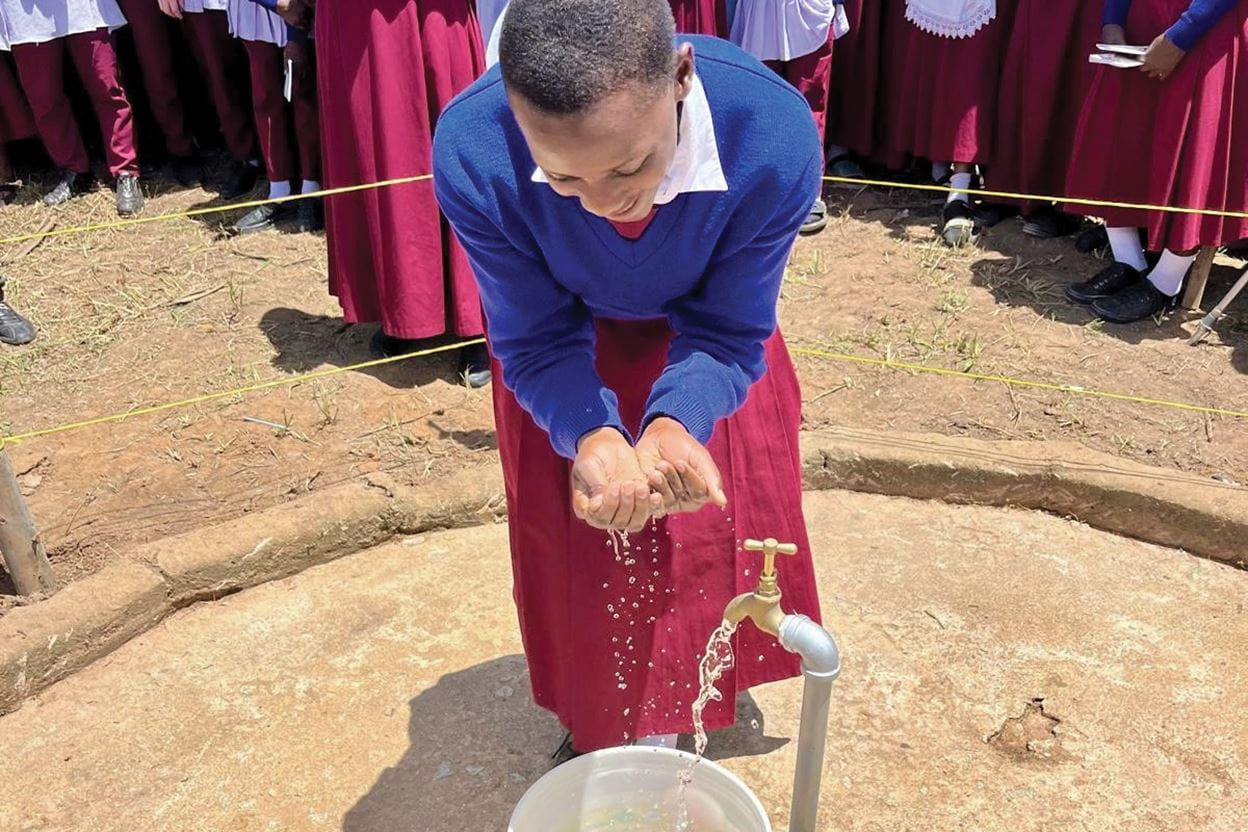 A girl drinking water from a well.