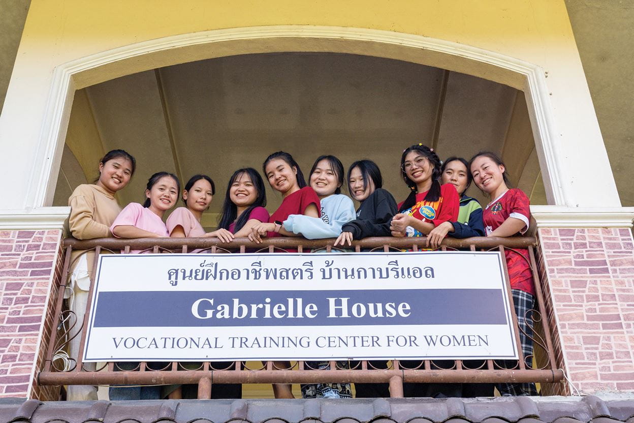 A group of smiling girls standing on the balcony of the Gabrielle House, where they live.