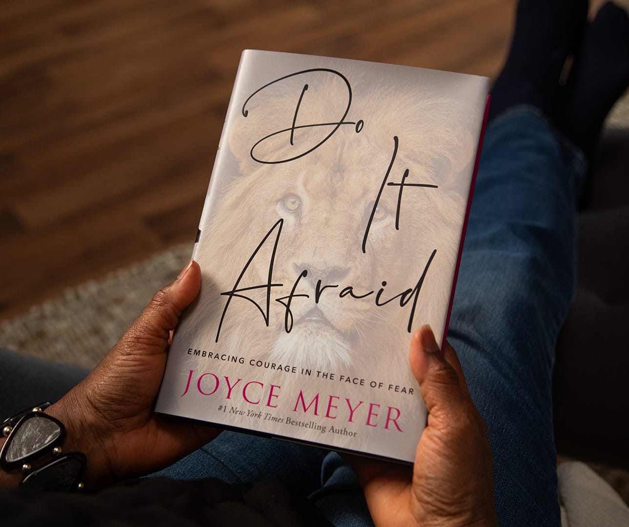 A woman holding the Do It Afraid hardcover book in her lap.