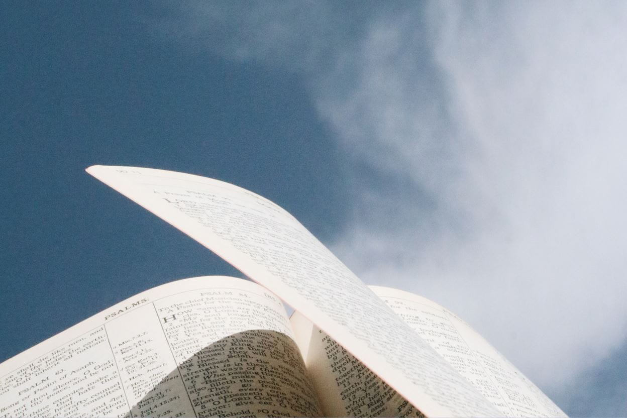 Open Bible ready for reading a daily devotional with a cloudy blue sky in the background.